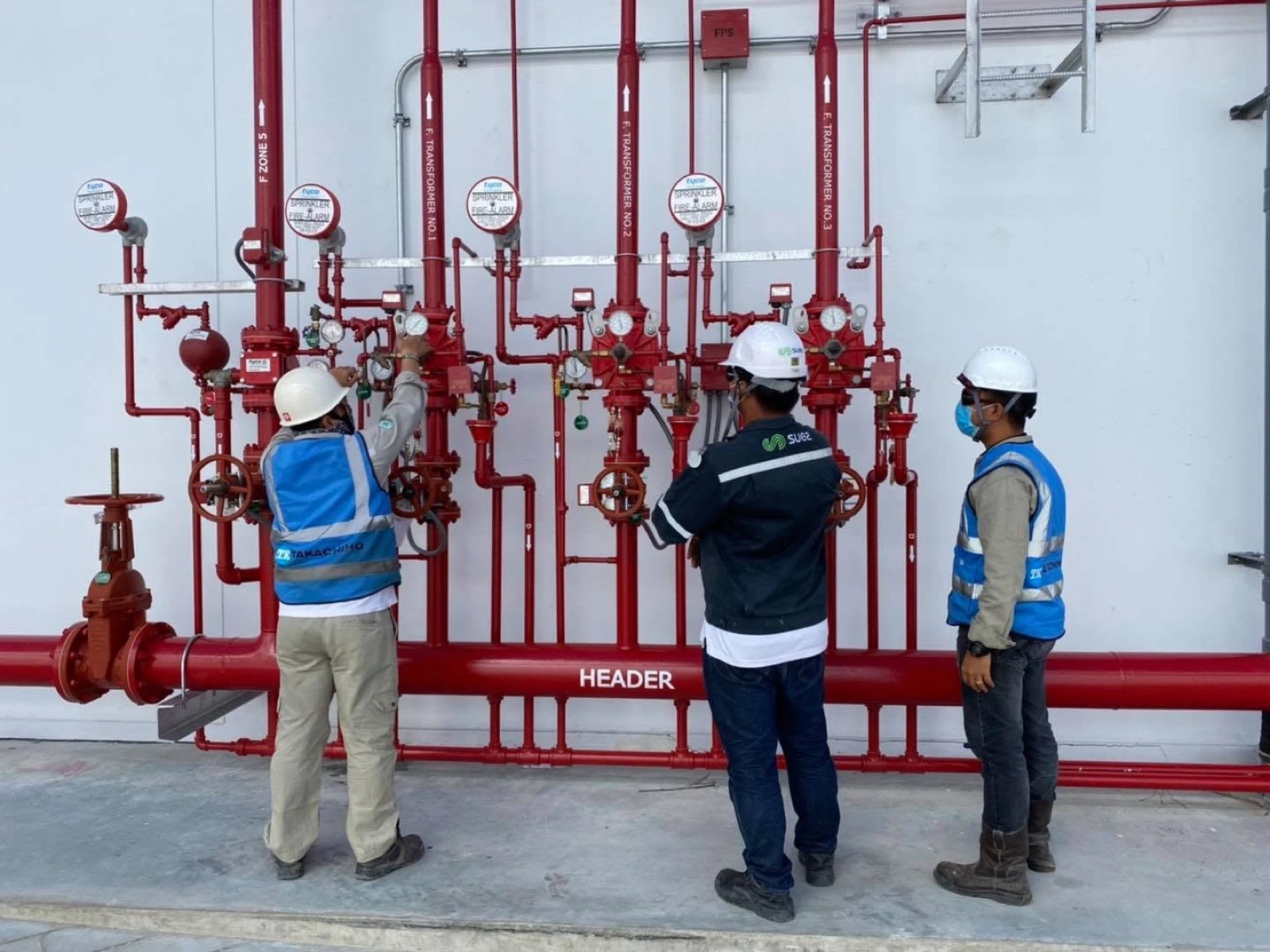 Engineers checking sprinkler alarm valves on a fire water header